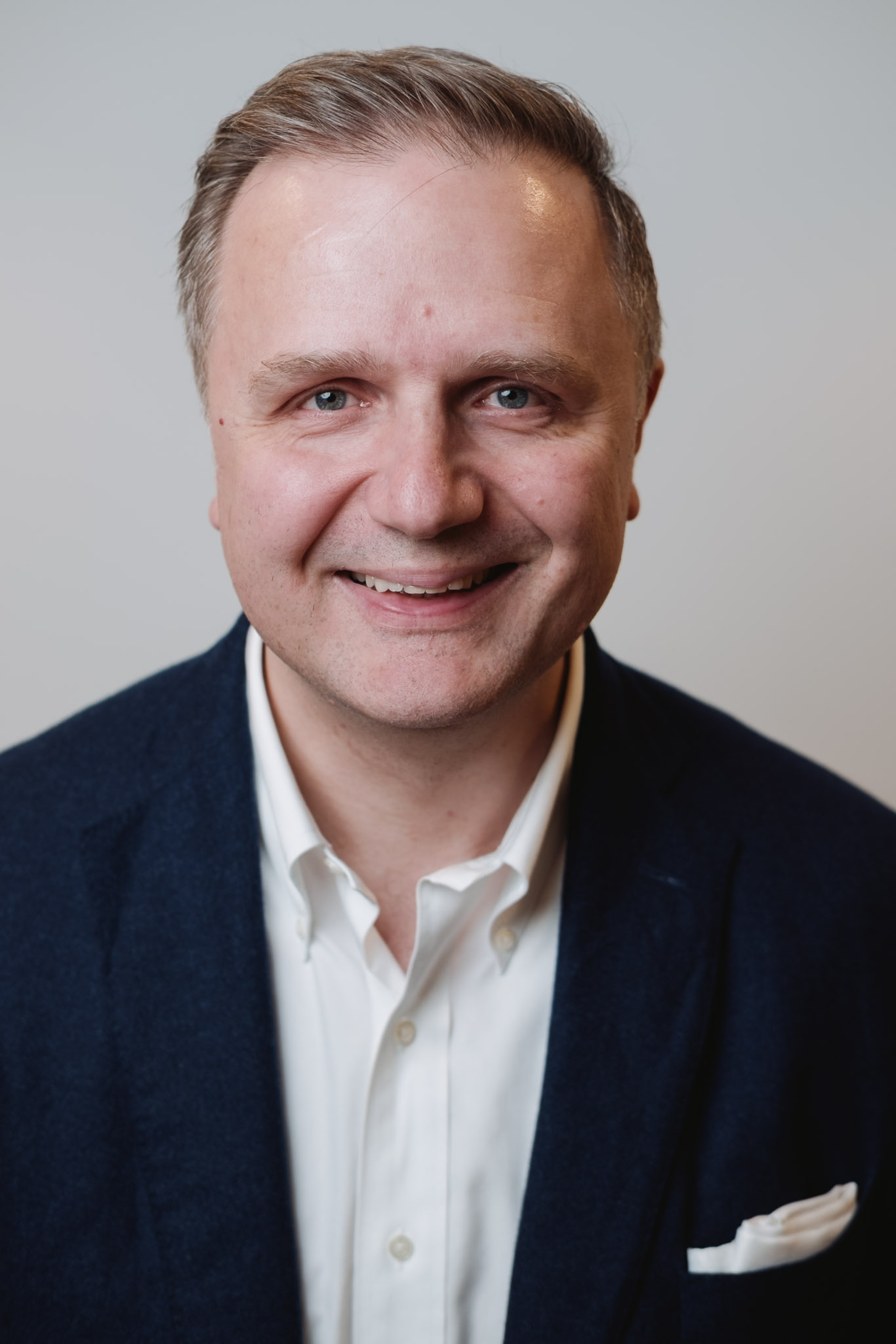 Senior executive portrait — natural studio lighting, warm expression.